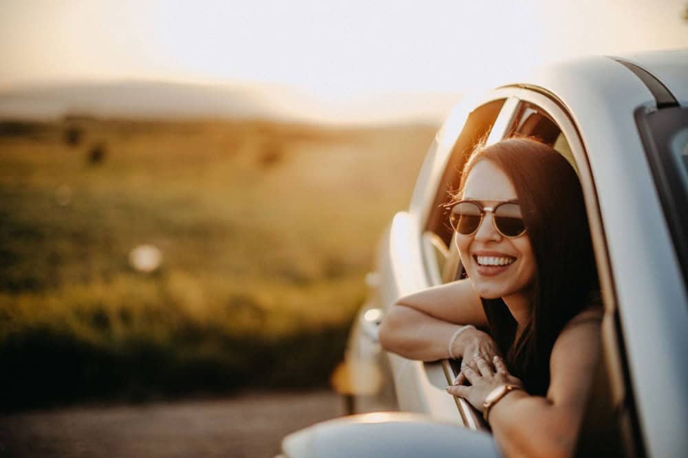 หญิงสาวสวมใส่แว่นกันแดดเลนส์ย้อมสีเพื่อปกป้องดวงตาจากแสงแดดขณะขับขี่รถยนต์